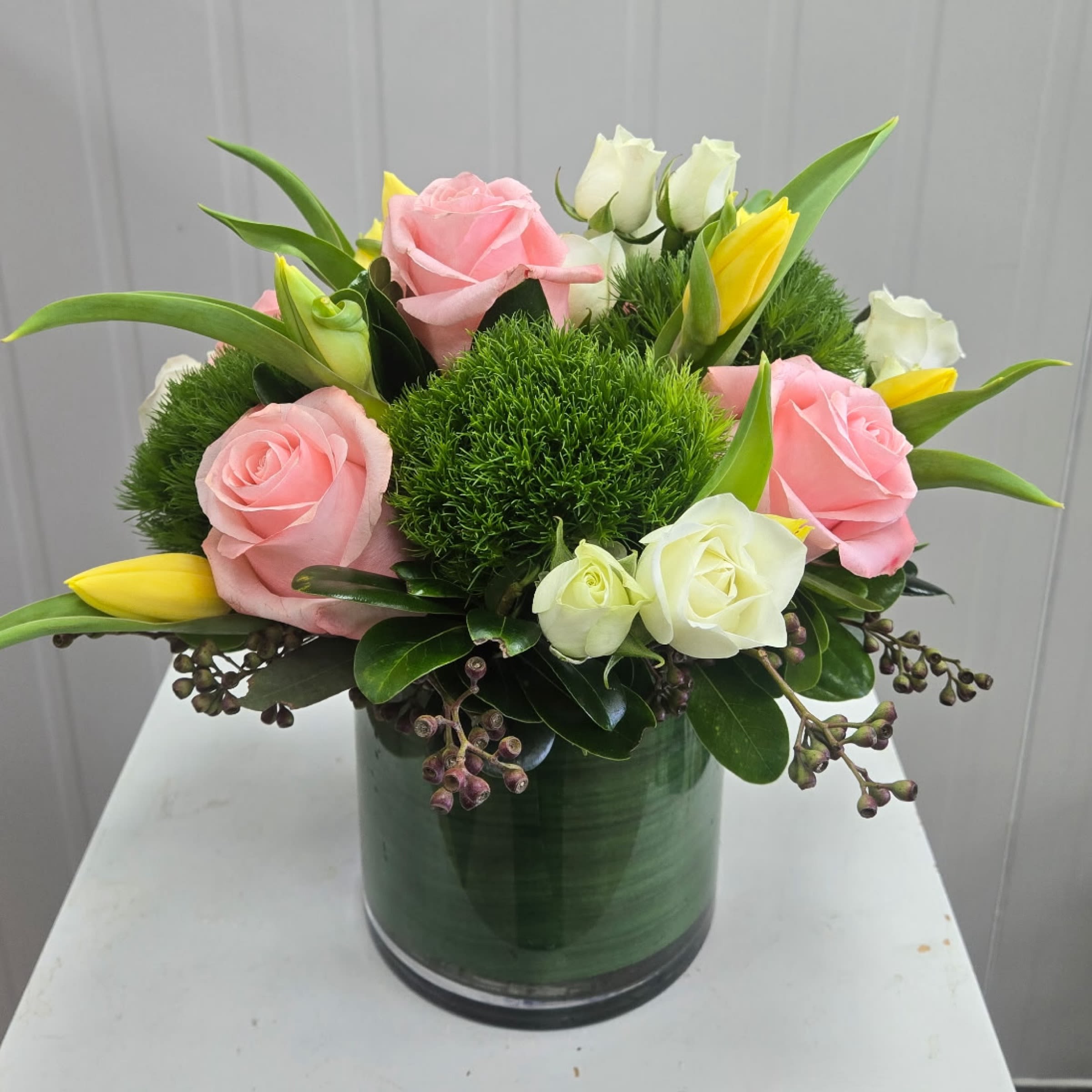 Spring Joy - This Arrangement includes Light Pink Roses, White Spray Roses, Green Trix and Yellow Tulips in a Glass Vase. Or as Similar as Possible. 