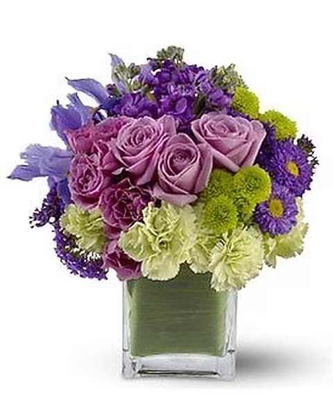 Teleflora's Mod About You - Express your passion with this mod bouquet of lavender roses, blue iris and asters, accented with touches of chartreuse. It's the perfect gift for a loved one and the cool tones and modern leaf-lined glass block vase make it an excellent choice for men, too!