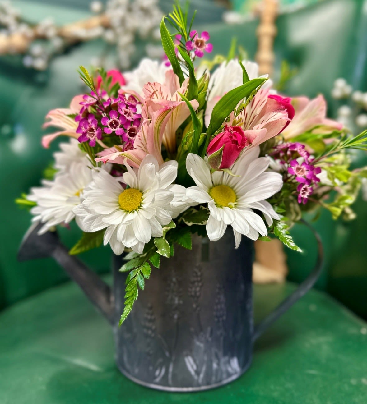 Spring Showers Bouquet - Spring Showers is a cute mix of flowers in a keepsake galvanized watering can with a lovely lavender flower motif. Pictured is the standard bouquet, for deluxe and premium we add additional blooms for a larger, more lush look. 