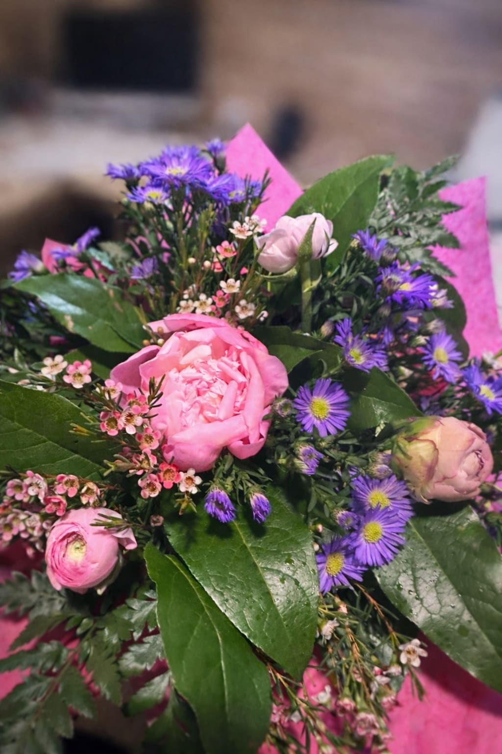 Sweet Meadow Whisper - Soft, romantic, and effortlessly charming—Sweet Meadow Whisper features lush pink peonies paired with delicate ranunculus, surrounded by airy lavender asters and fresh greenery. Hand-tied and wrapped with care, this bouquet feels like a walk through a blooming spring meadow. Perfect for celebrating love, sending encouragement, or simply brightening someone’s day—because every stem is designed to deliver a little bit of love. 