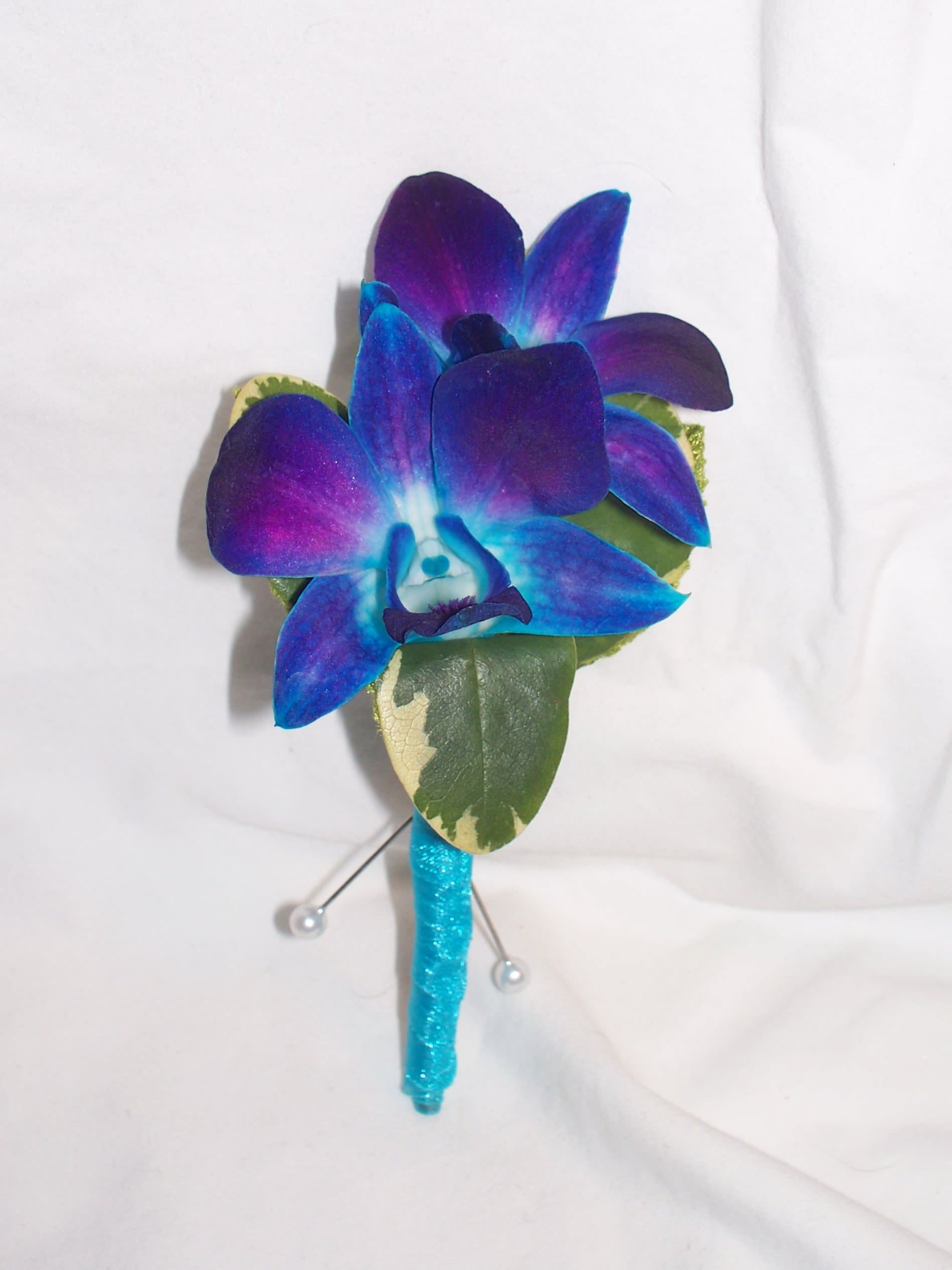 Blue and purple orchid boutonniere with a glittery turquoise stem wrap