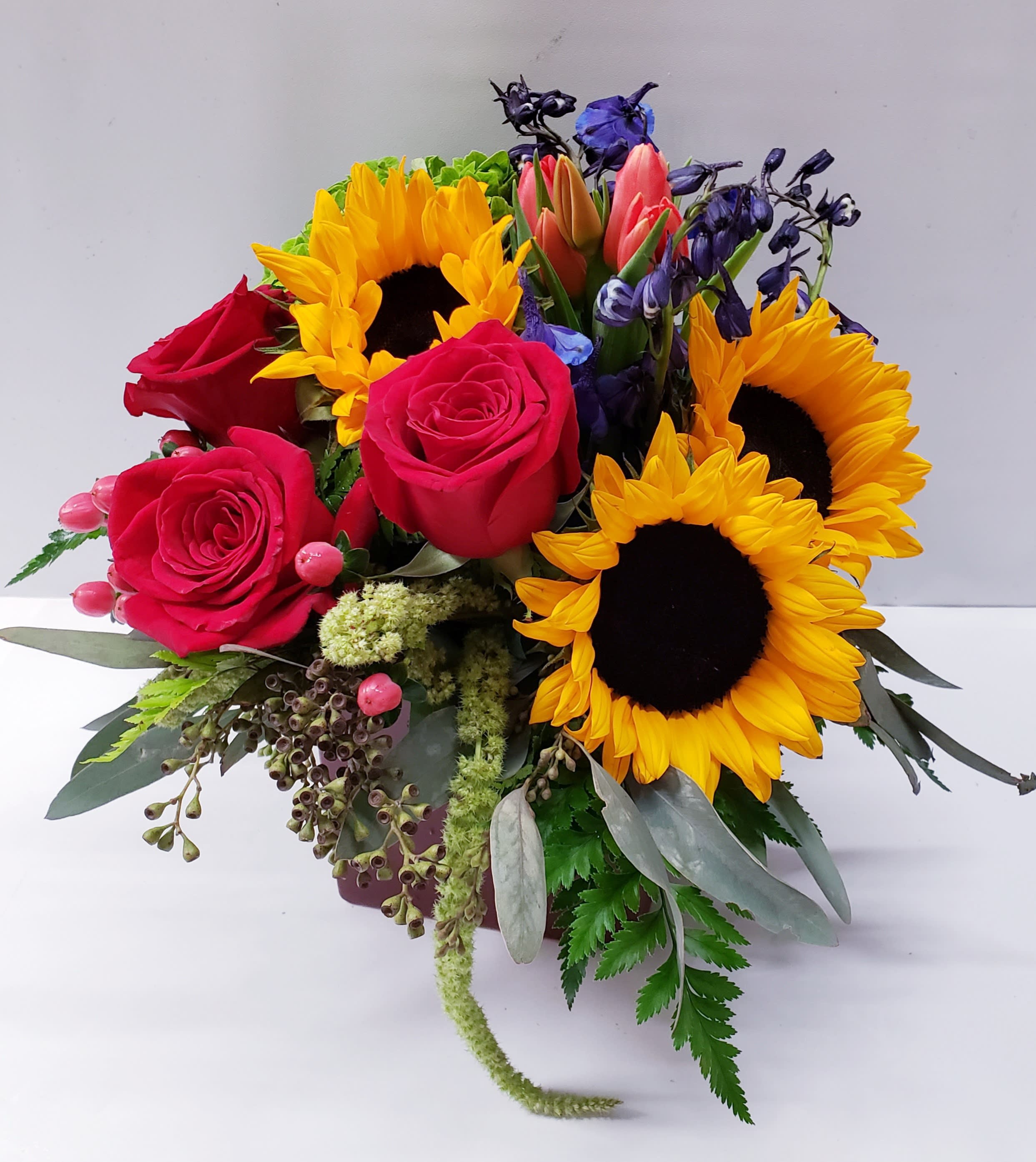 Bouquet of red roses and sunflowers with purple blooms