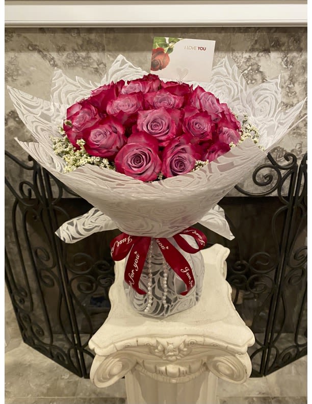 Bouquet of pink roses wrapped in white paper with a red ribbon