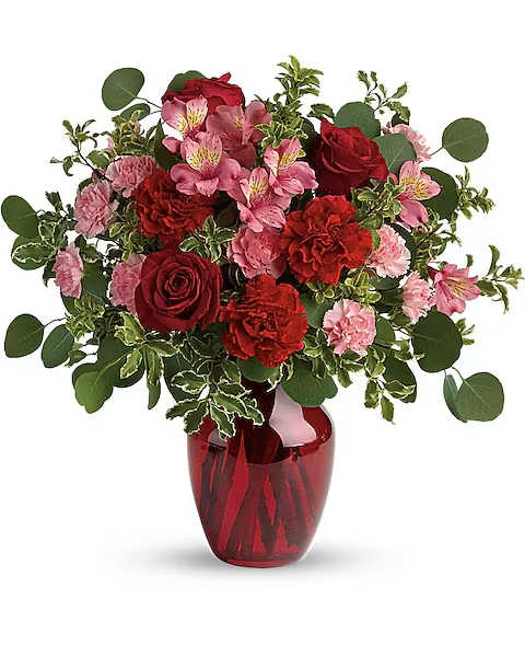 Blooming Belles Bouquet - The belle of the ball! Arranged in a ruby red vase, this romantic bouquet of rich red roses and delicate pink alstroemeria is a beautiful statement of love and devotion. Red roses, pink alstroemeria, red carnations, and miniature pink carnations are accented with silver dollar eucalyptus and pitta negra. Delivered in a ruby rose vase.