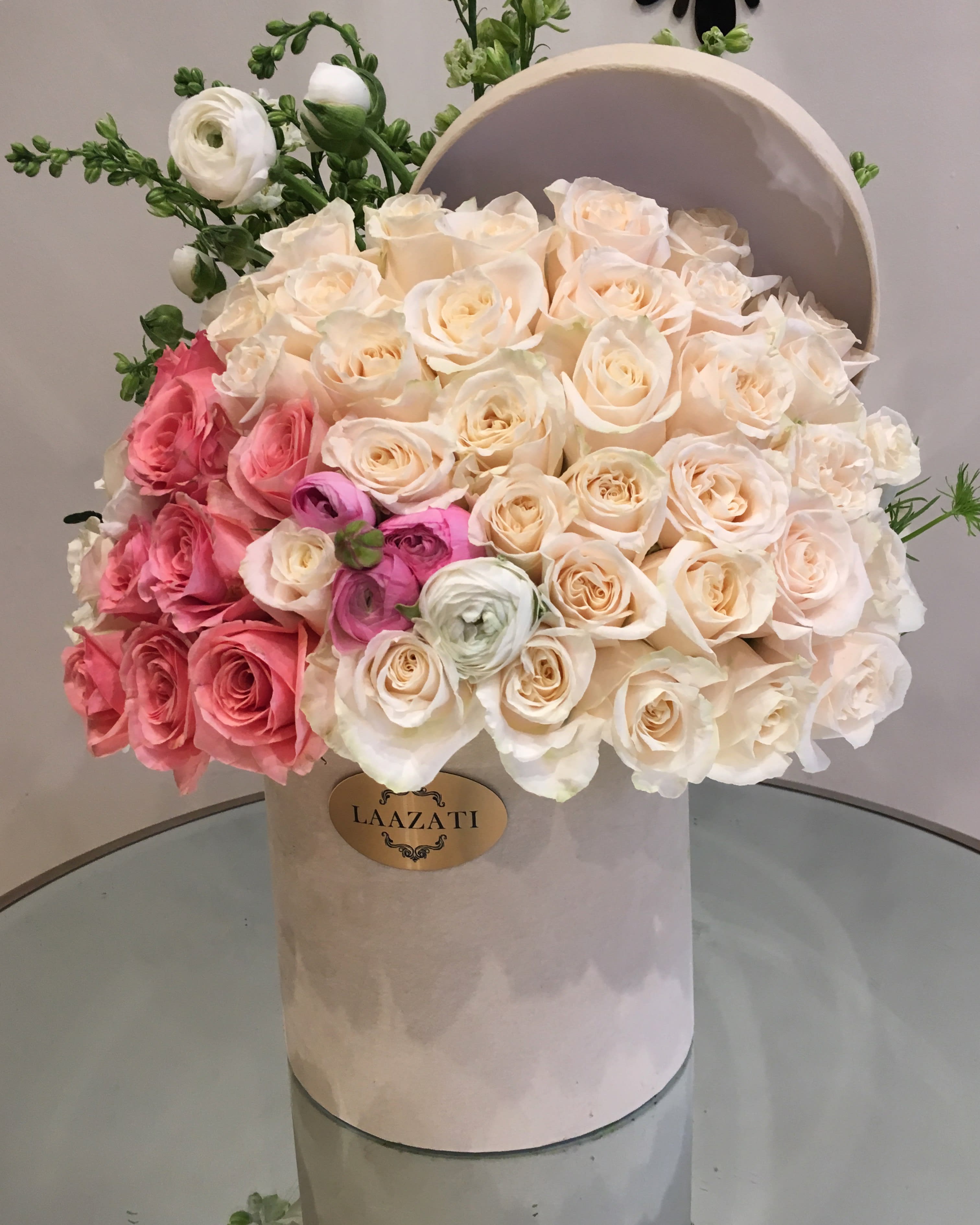 Bouquet of cream and pink roses in a round hatbox