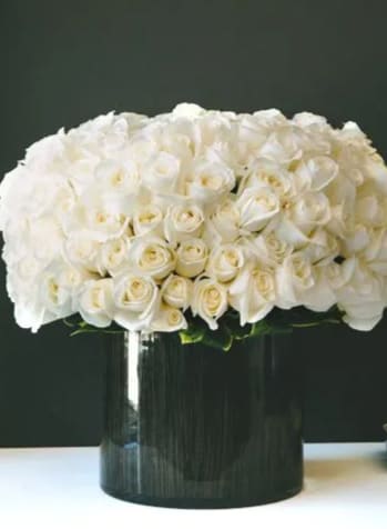 White rose arrangement in a black vase