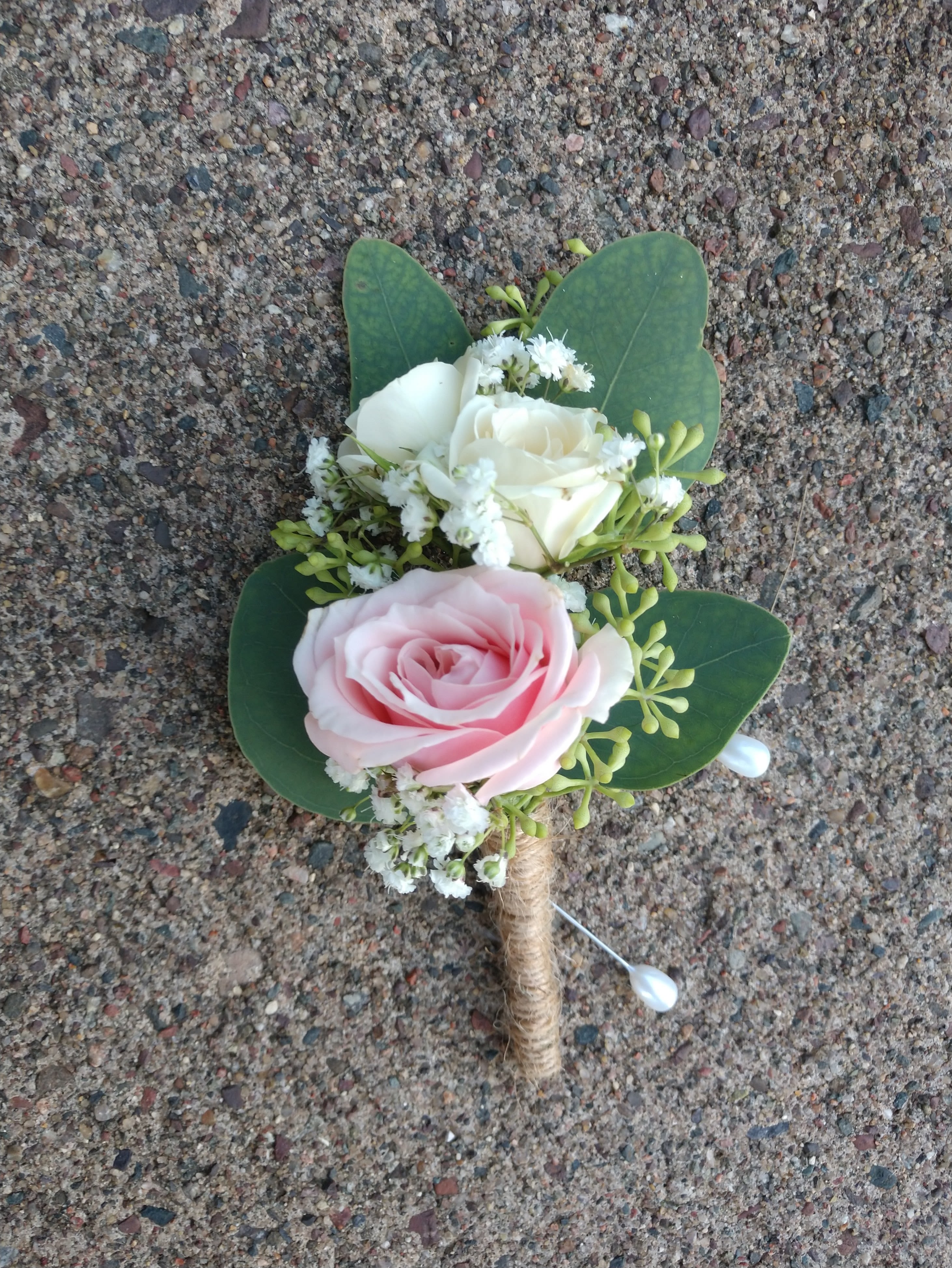 Small boutonniere with pink and white roses and green leaves