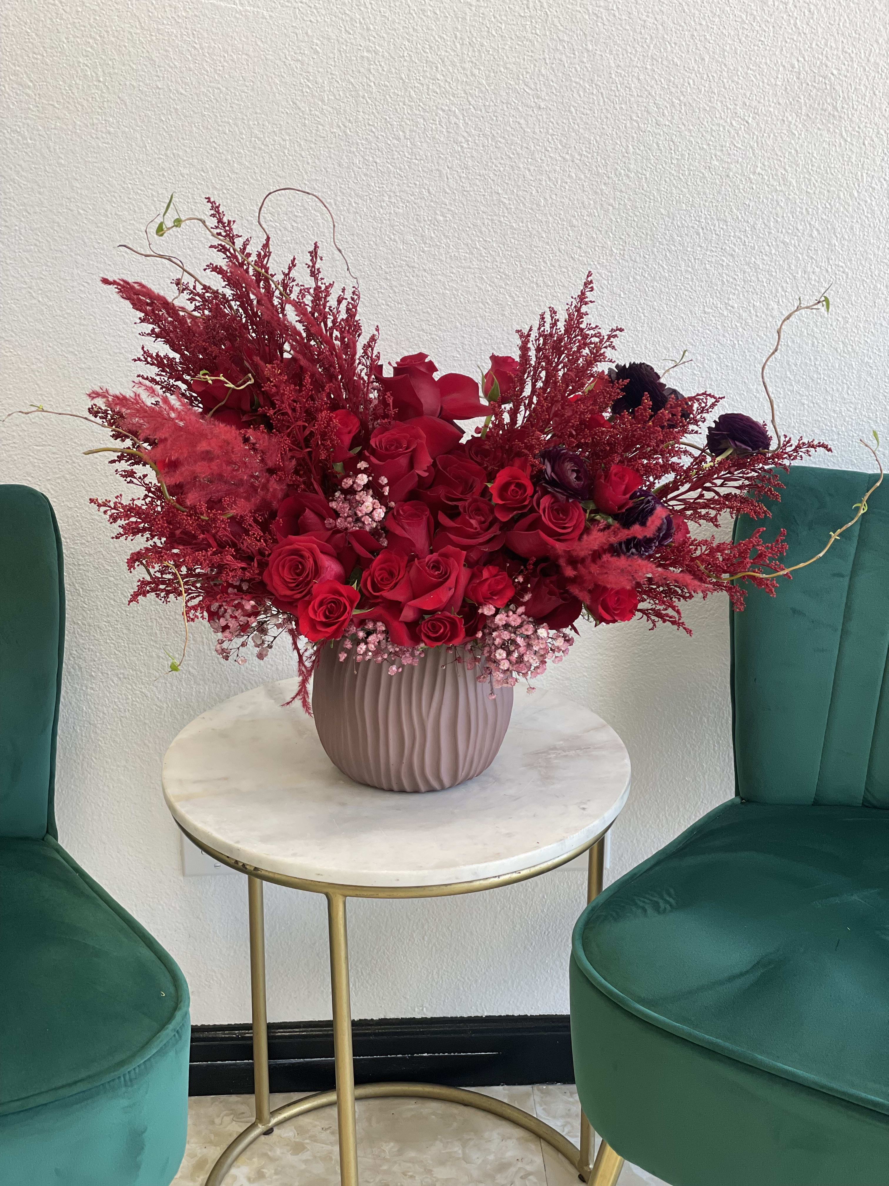 Red rose arrangement in a ribbed pink vase on a small round table