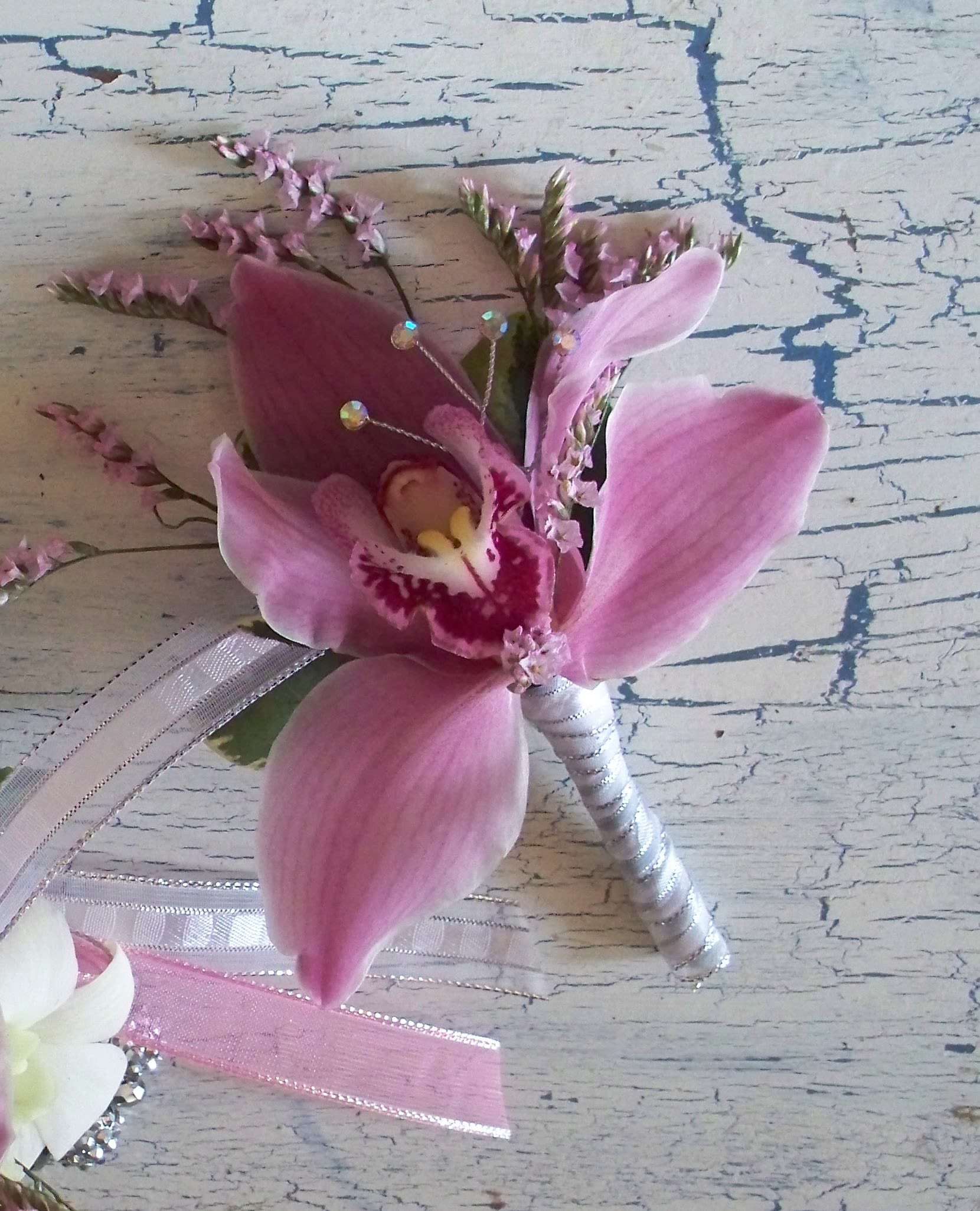 Pink orchid boutonniere with ribbon and small decorative accents