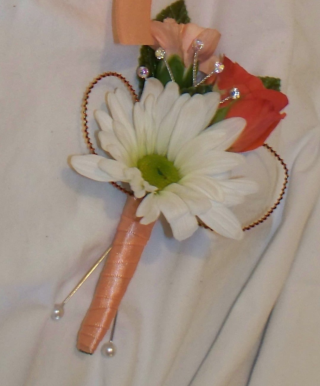Small boutonniere with a white daisy and peach-orange flowers