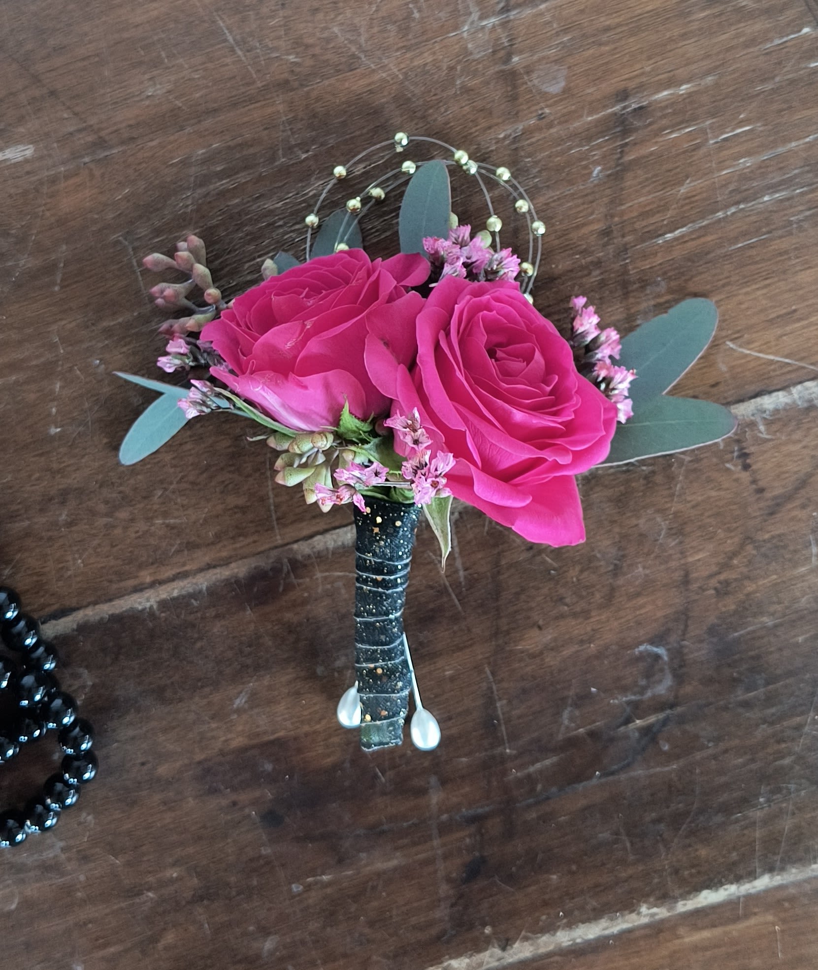 Pink rose boutonniere with small filler flowers and eucalyptus