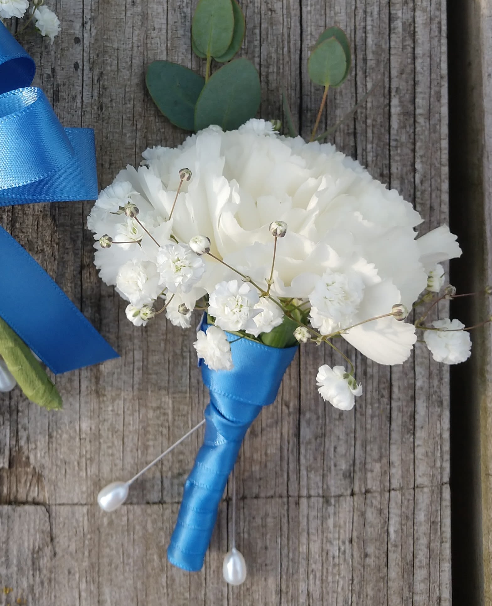 White boutonniere with blue ribbon wrap and small white filler flowers