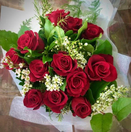 Bouquet of red roses with white filler flowers and green foliage