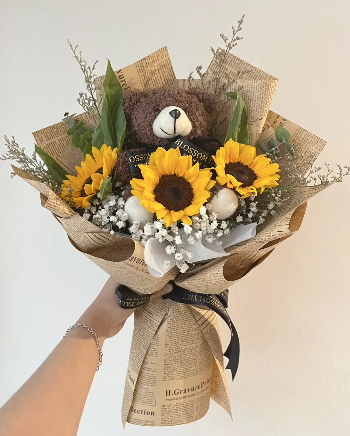 Bouquet of sunflowers with a teddy bear and newspaper-style wrapping