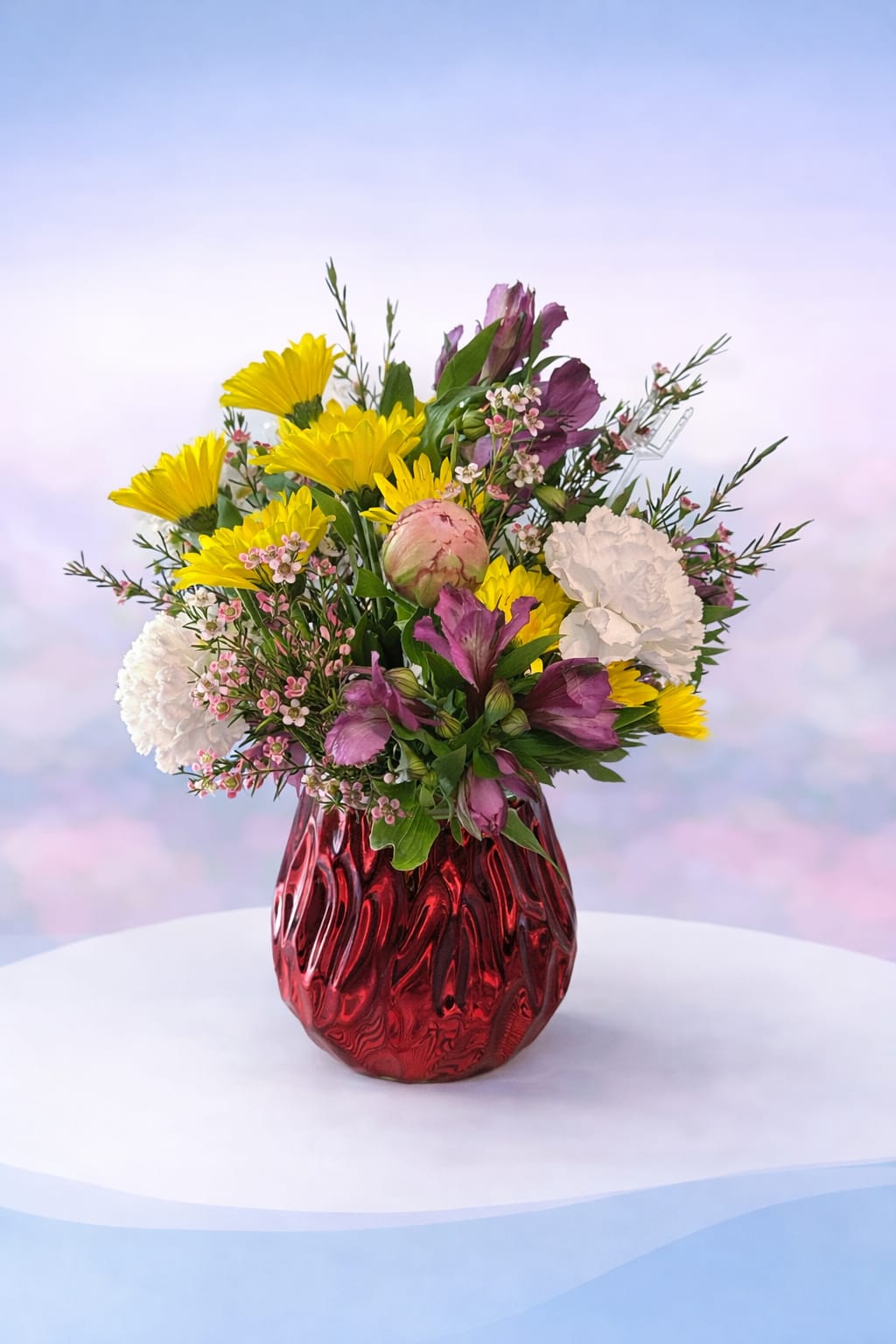 Ruby Peony Radiance - Bold, vibrant, and full of charm—Ruby Peony Radiance features a lush peony nestled among cheerful yellow daisies, soft white blooms, and rich purple accents. The peony adds a romantic, full-bodied focal point that brings softness and elegance to this otherwise bright and playful design.