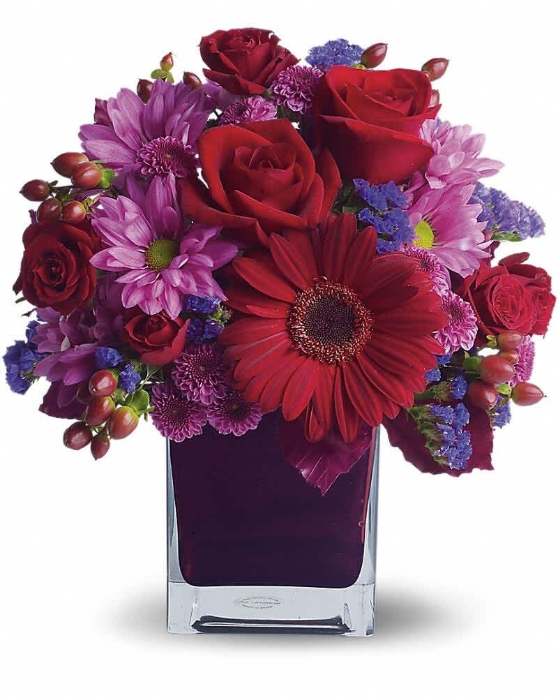 Compact bouquet of red roses and gerbera with purple mums in a square glass vase