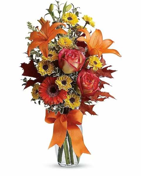 Burst of Autumn - A veritable burst of beauteous blooms in autumn shades of flaming orange and yellow – including roses, lilies and more - is mixed with a handful of oak leaves, then delivered in a clear glass vase adorned with a bright satin ribbon. A splendid bouquet for birthdays or any fall occasion.