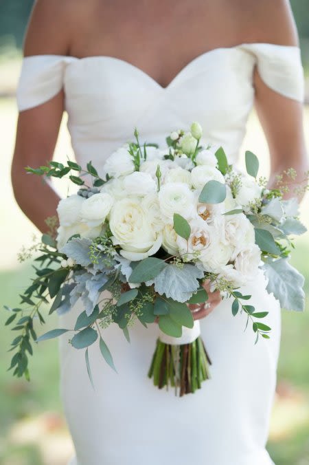 Bride holding a white bouquet with greenery