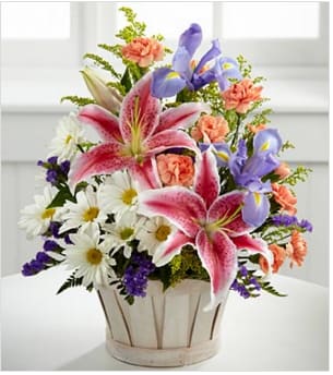Bouquet of pink lilies, purple irises, and white daisies in a wooden basket