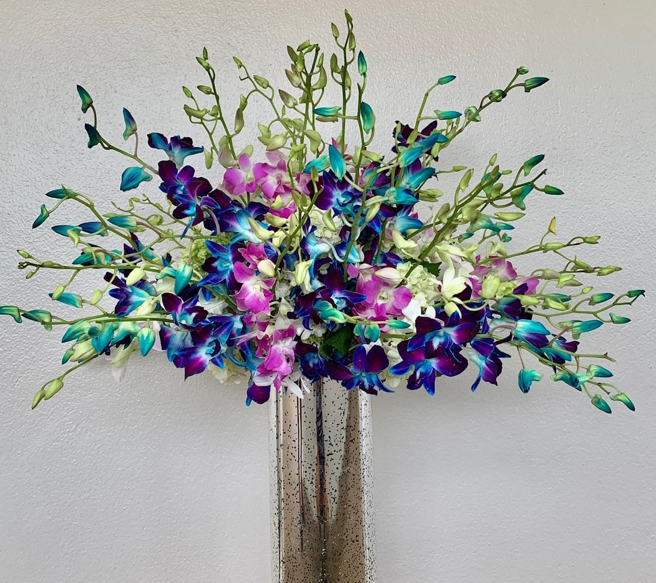 Colorful orchid arrangement in a tall metallic vase
