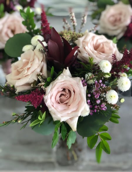 Bouquet of pale pink roses with burgundy accents and mixed greenery