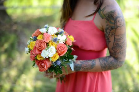 Woman holding a colorful bouquet of roses and small white flowers