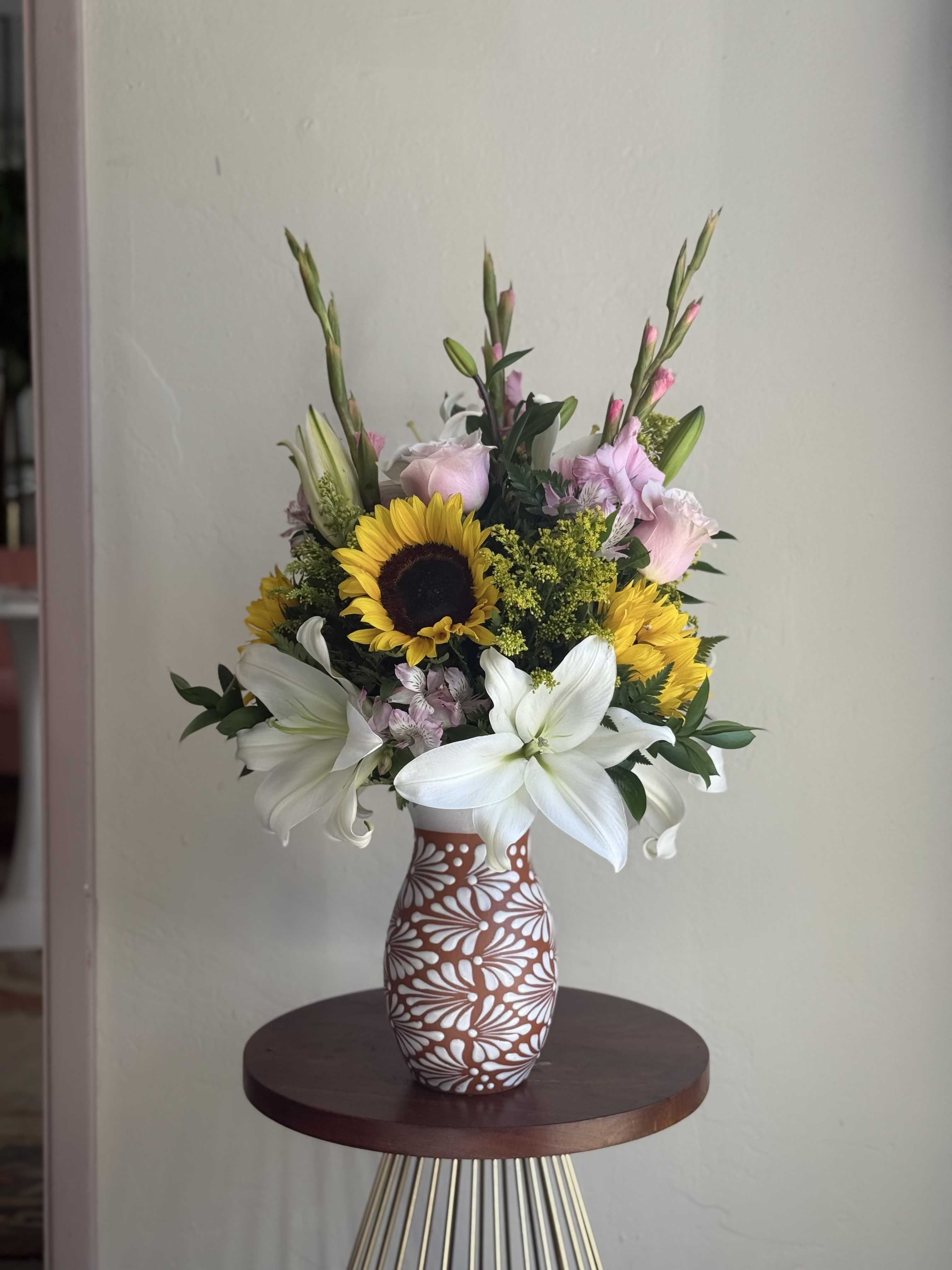 Mixed bouquet with sunflowers and white lilies in a patterned vase