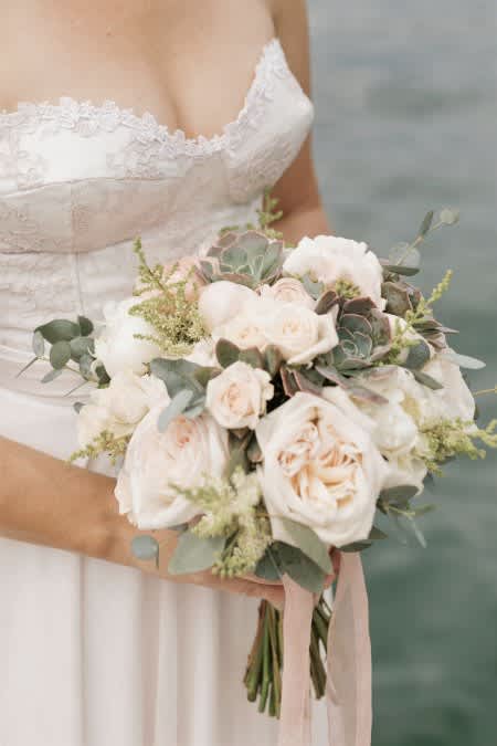 Bride holding a white and blush bouquet with greenery