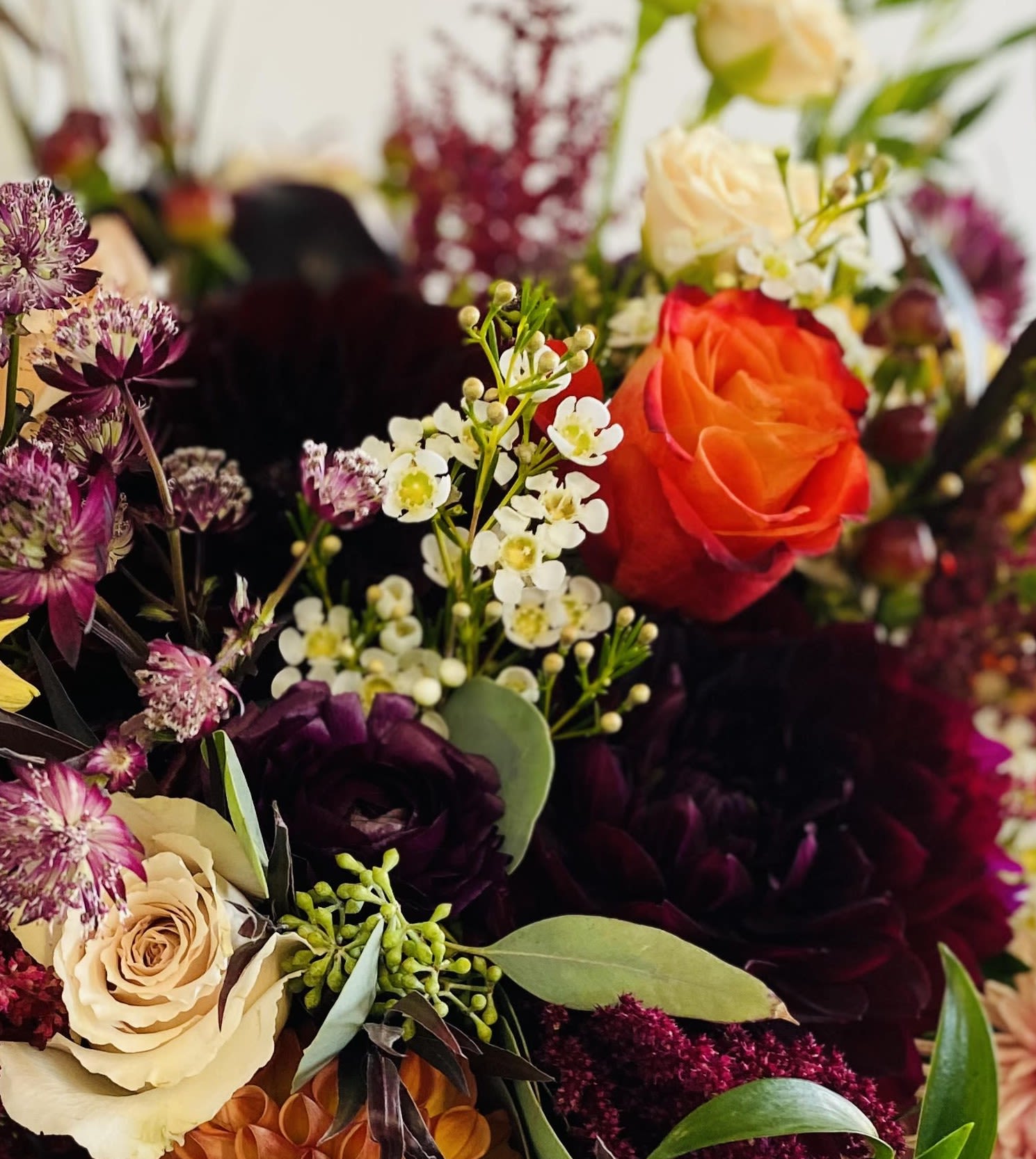 Mixed bouquet with orange, cream, and dark purple roses