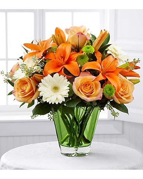 Birthday Wishes - Send bright and happy wishes for the ultimate birthday celebration with this colorful arrangement. Peach roses, orange Asiatic lilies, white gerbera daisies, green button poms and lush greens are perfectly arranged in a clear green glass vase to create a beautiful addition to their birthday festivities.