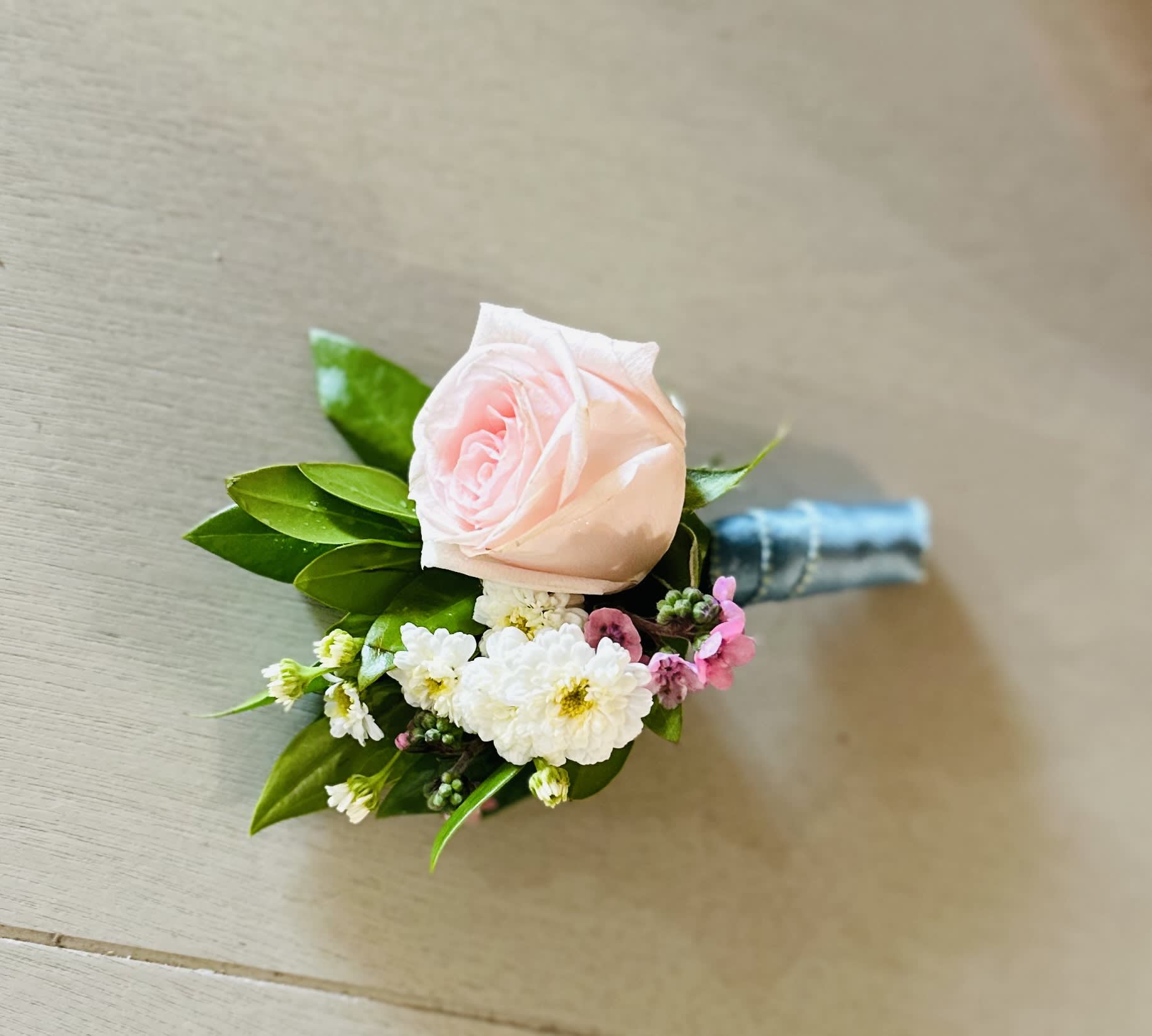 Pink rose boutonniere with small white and pink flowers