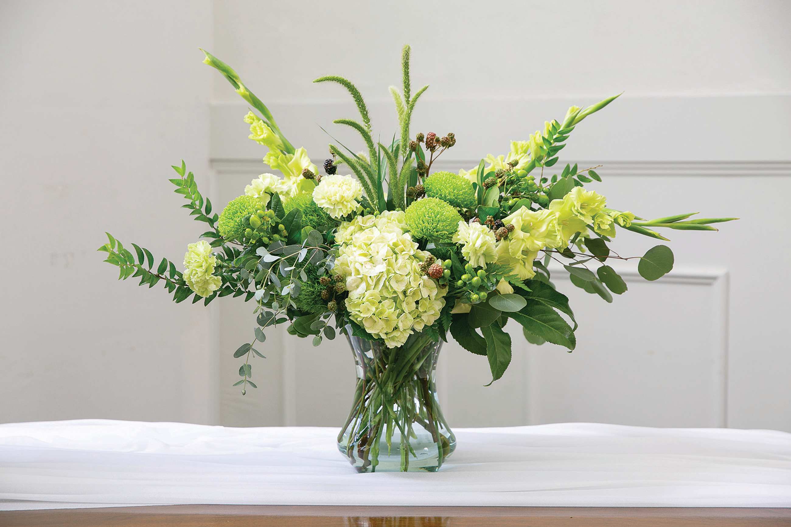 Green floral arrangement in a clear glass vase