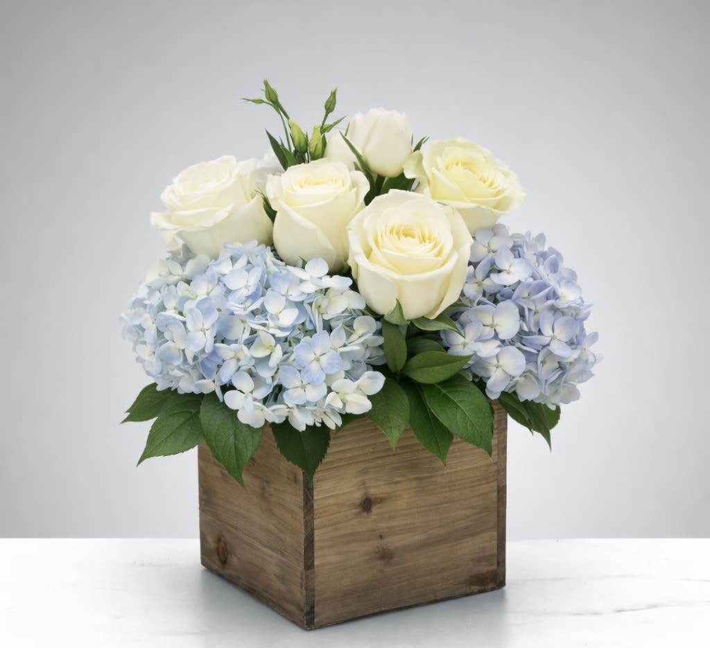 White roses and pale blue hydrangeas in a wooden box