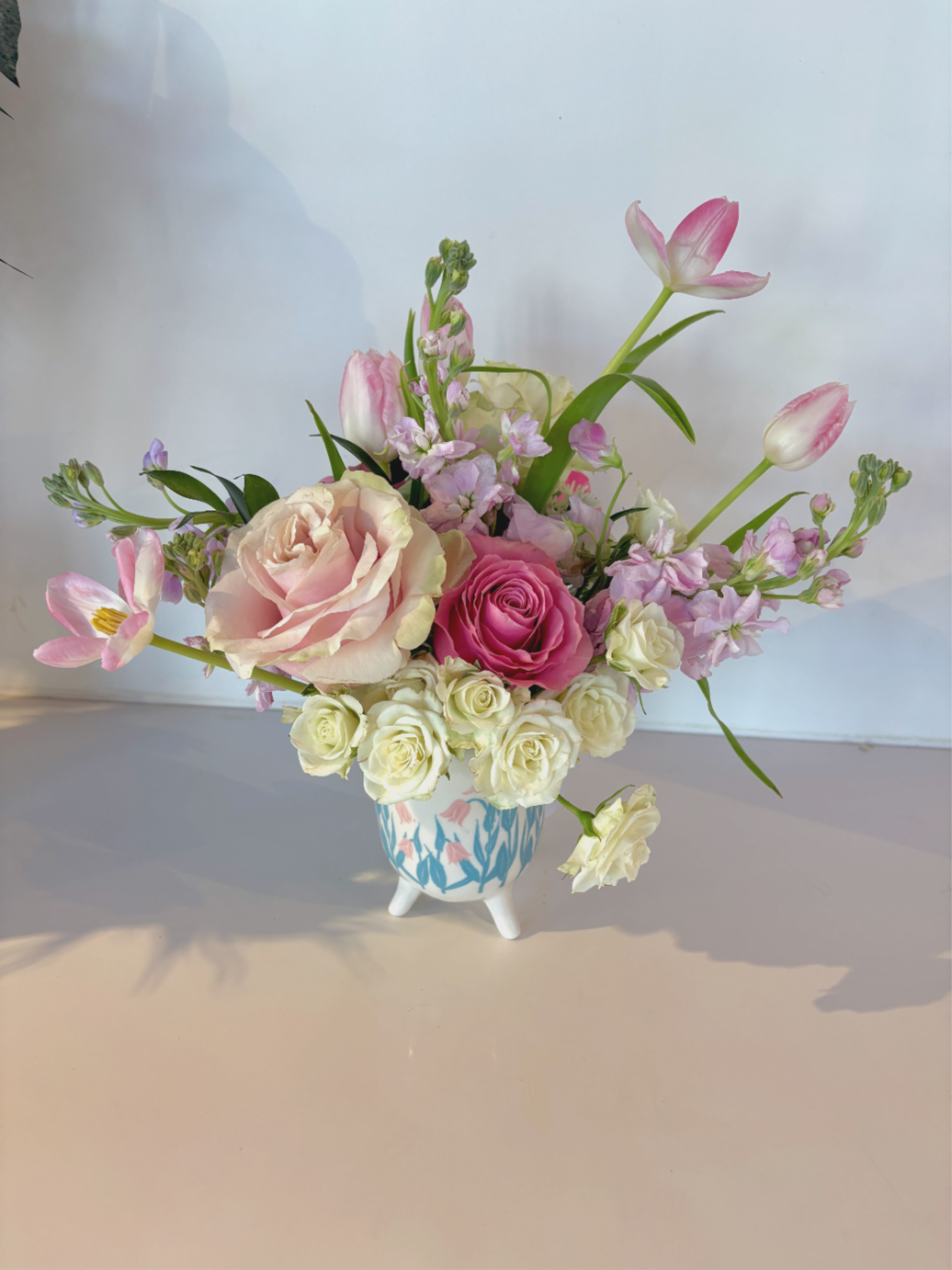 The Blush Garden  - Soft, feminine &amp; alittle whimsical- just like us &amp; like a mini spring garden!  This is one everyone will adore from mom to a birthday gal to a thinking of you moment!  This footed vase is so cute and is filled with tulips, spray rose, garden roses, sweet stock and a hit of green and wax flower.  It smells as good as it looks and can't help but make anyone blush! 