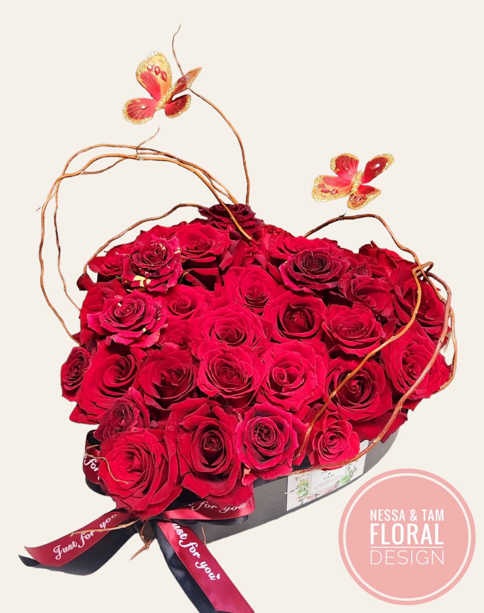 Heart-shaped box of red roses with butterfly picks
