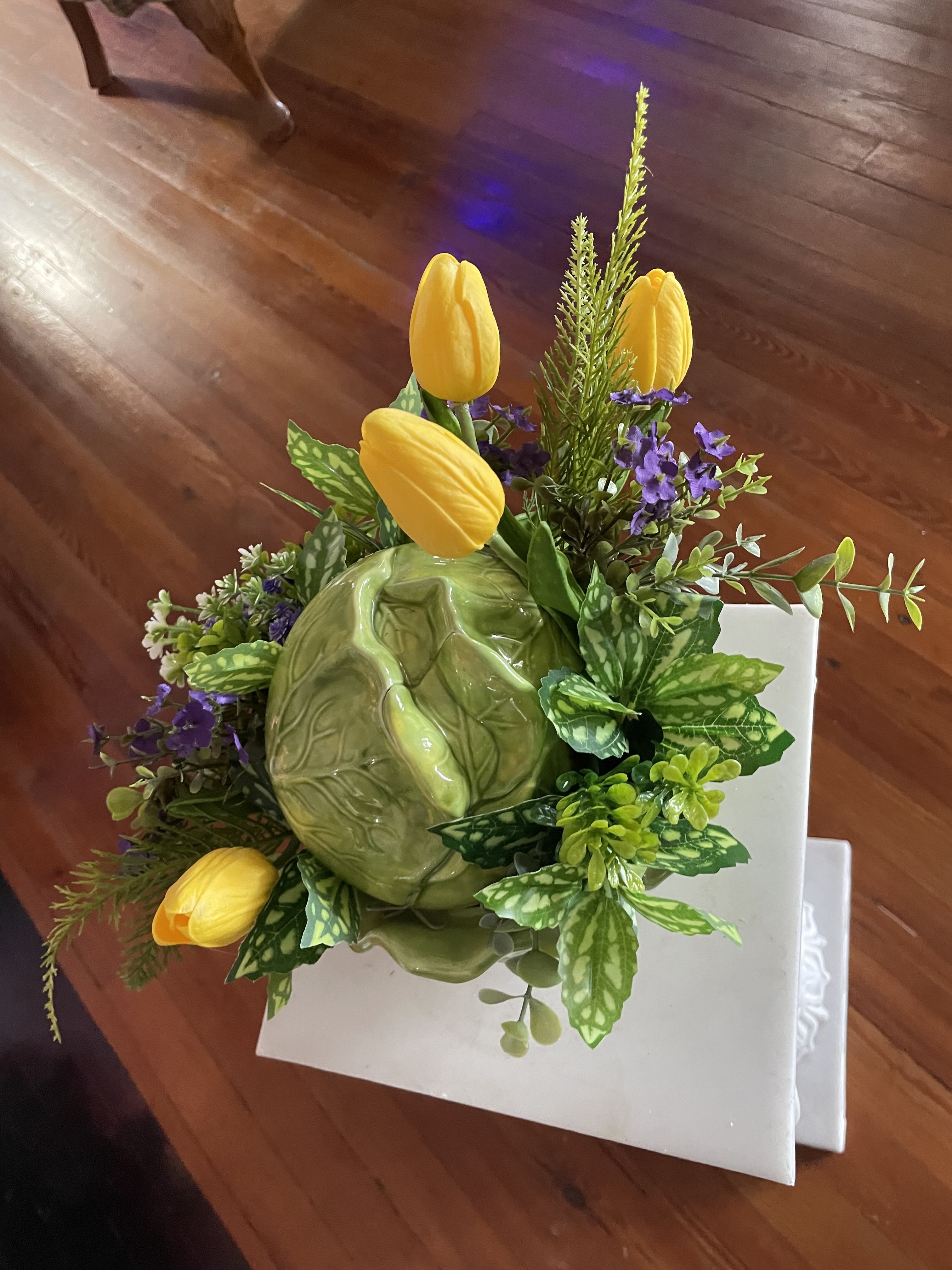 Spring Silk Garden ceramic cabbage - Designed in a ceramic cabbage . A silk swag made of white and purple silk flowers accented with greens.  A perfect sentiment to send in memory of a loved one. 