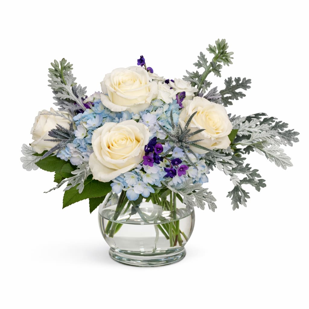 White roses and blue flowers in a clear glass vase