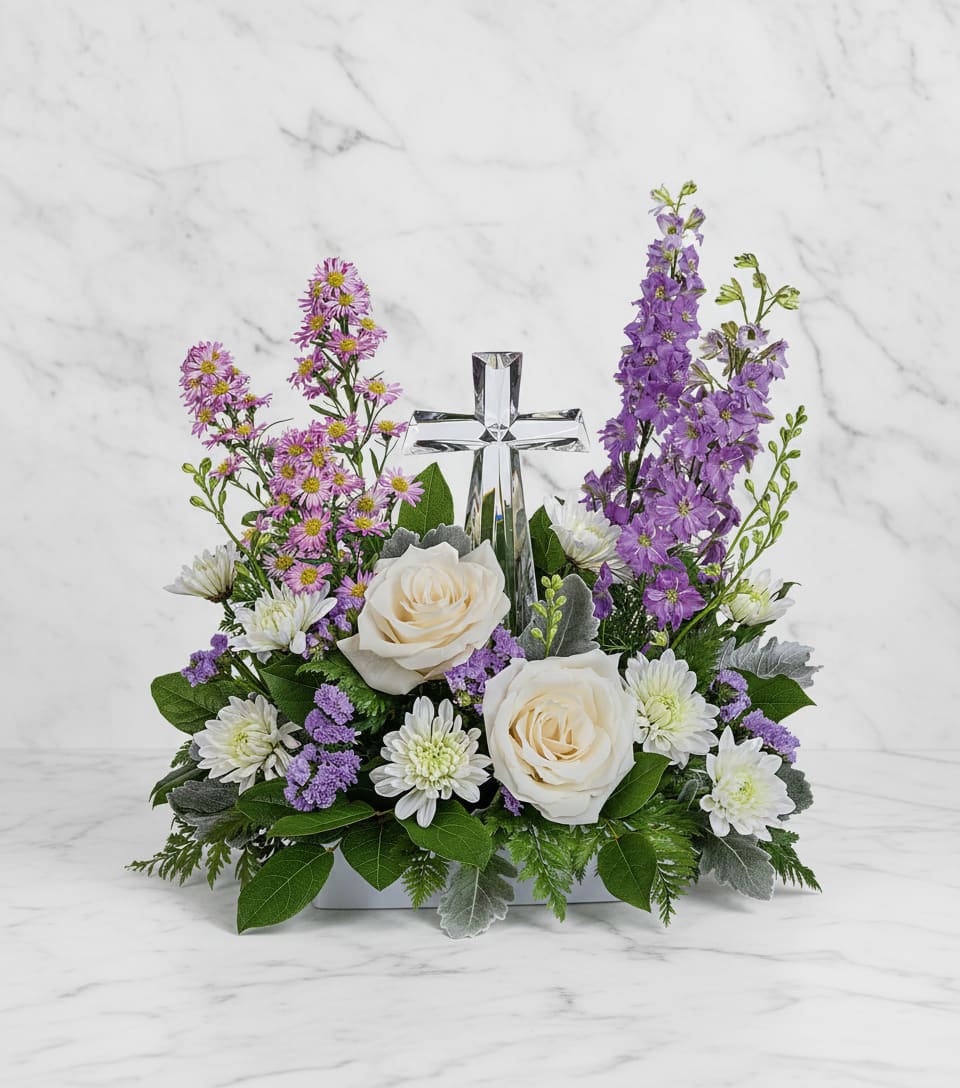 Poised with Love Bouquet - Soft and serene, this artistic array of cream and lavender blooms around a radiant crystal cross keepsake is a heartfelt expression of love.