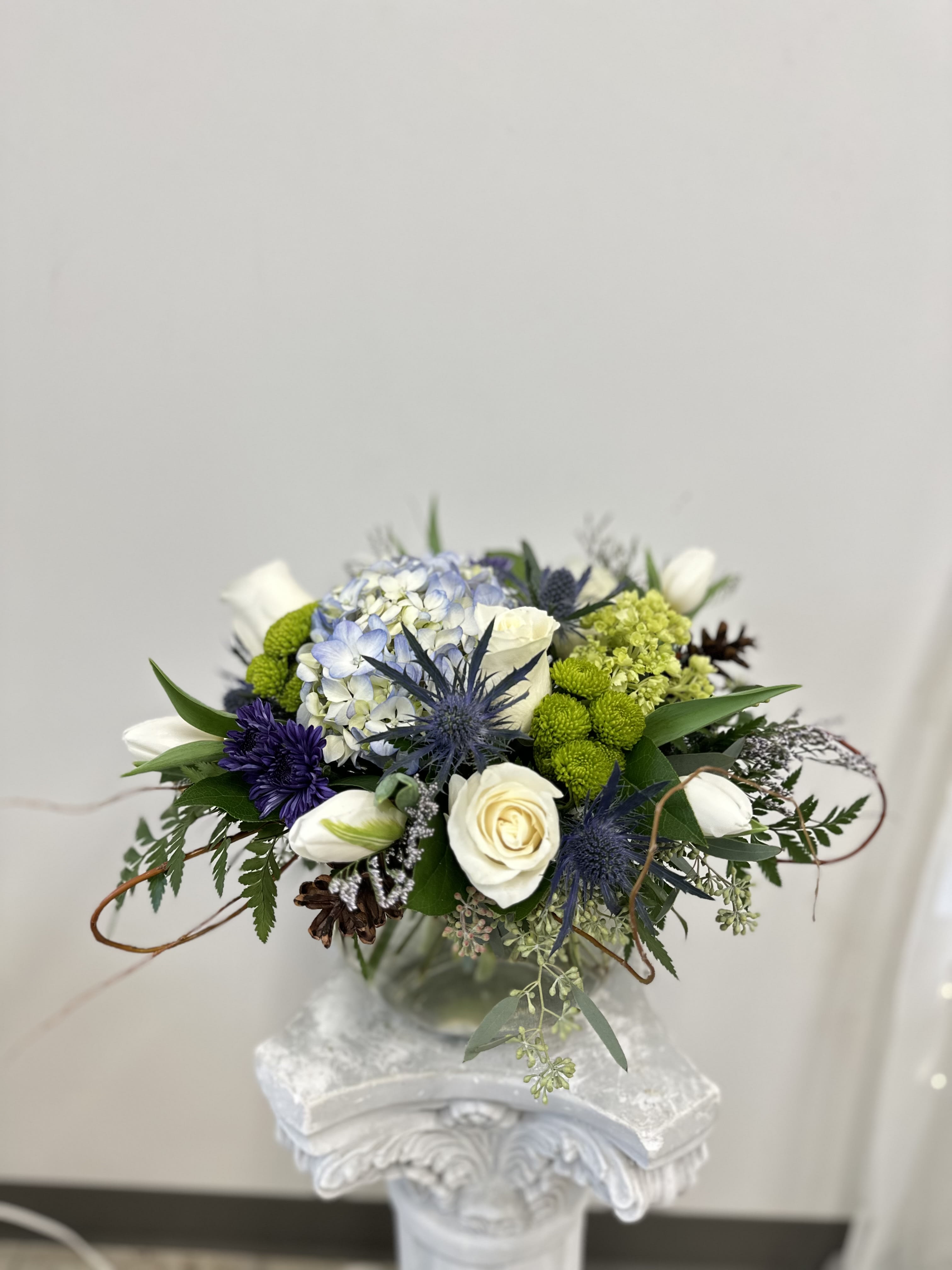 Whisper of Blue by Westford Florist Art by Veny - Transform your living space into a whimsical paradise with the enchanting Whisper of Blue flower arrangement from Westford Florist Art by Veny. Expertly crafted to enhance any room, this stunning bouquet features an exquisite blend of vibrant blues and serene whites, making it the perfect accent for your décor. Whether nestled in a bubble bowl, cube, or cylinder vase (availability permitting), each piece is designed not just to beautify but to uplift your spirit. Elevate your home with this floral masterpiece and indulge in a daily dose of joy that captures nature’s grace at its finest. Treat yourself to the beauty you deserve!