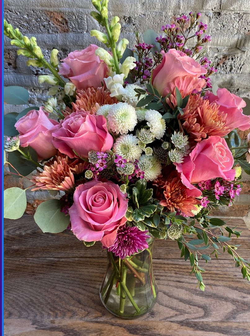 Pink roses and mixed blooms arranged in a glass vase