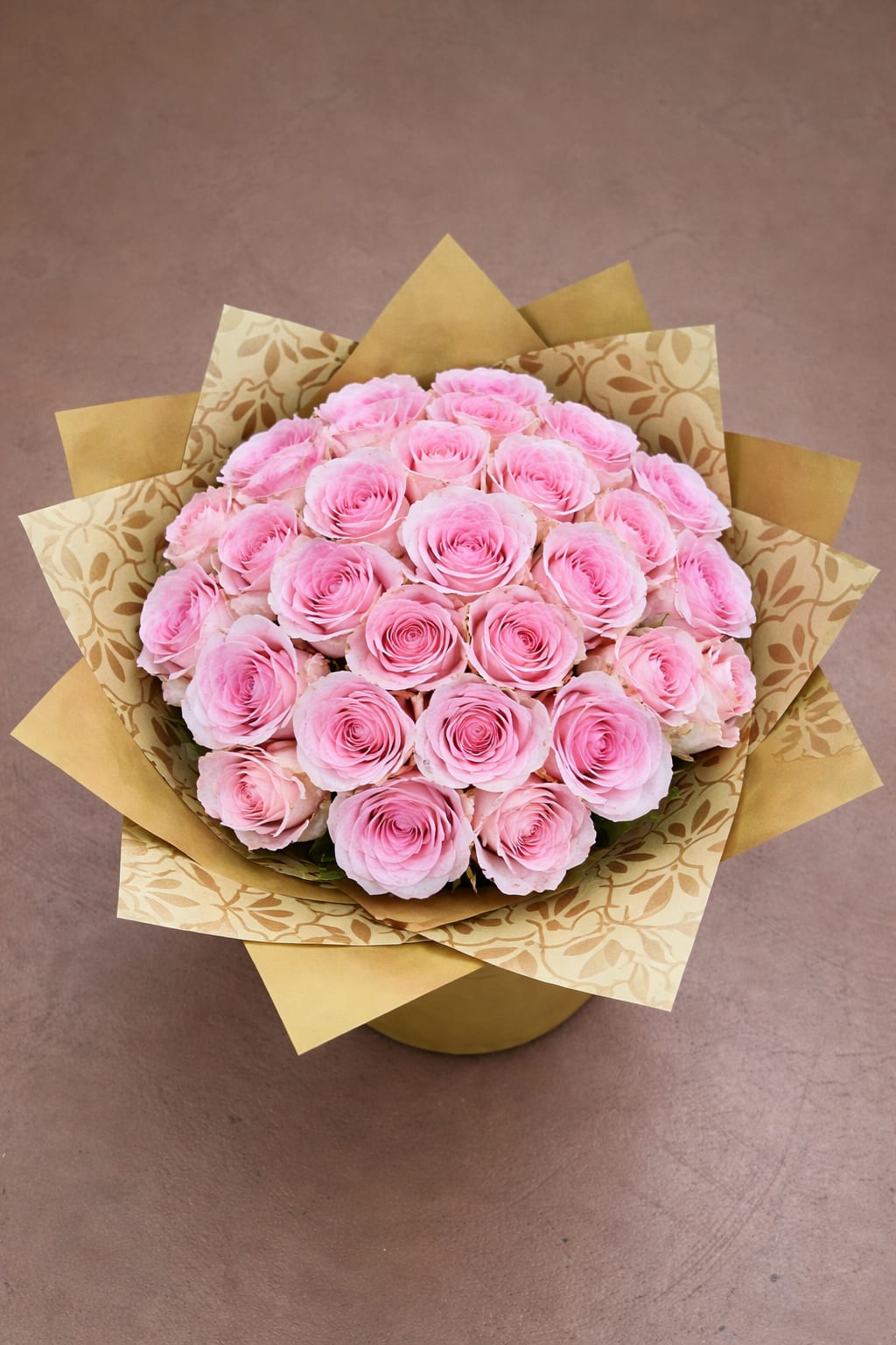Bouquet of pink roses wrapped in patterned gold paper