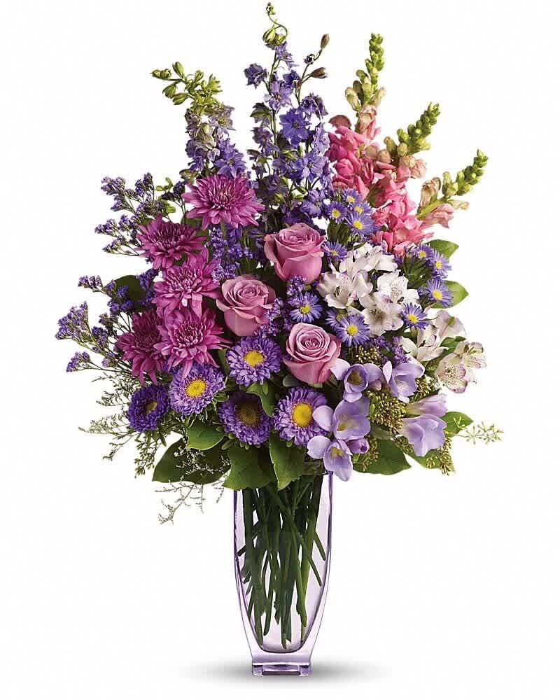Tall arrangement of pink and purple flowers in a slender lavender glass vase