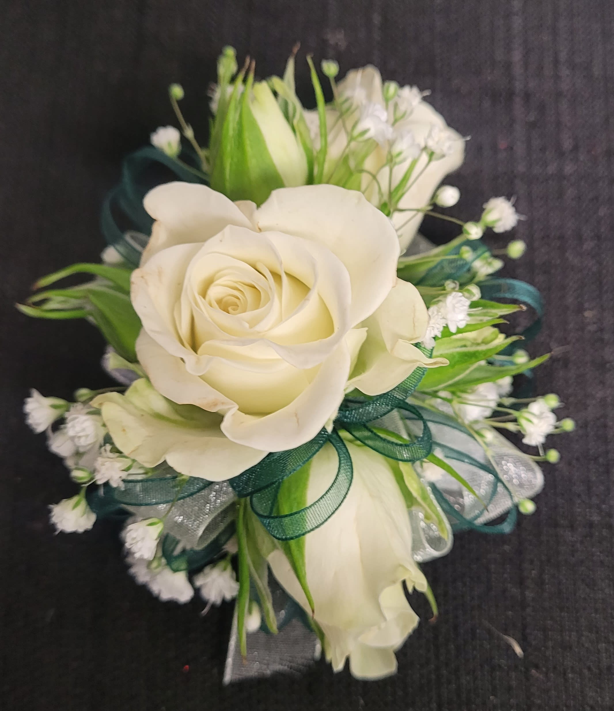 White rose corsage with green ribbon and small white filler flowers