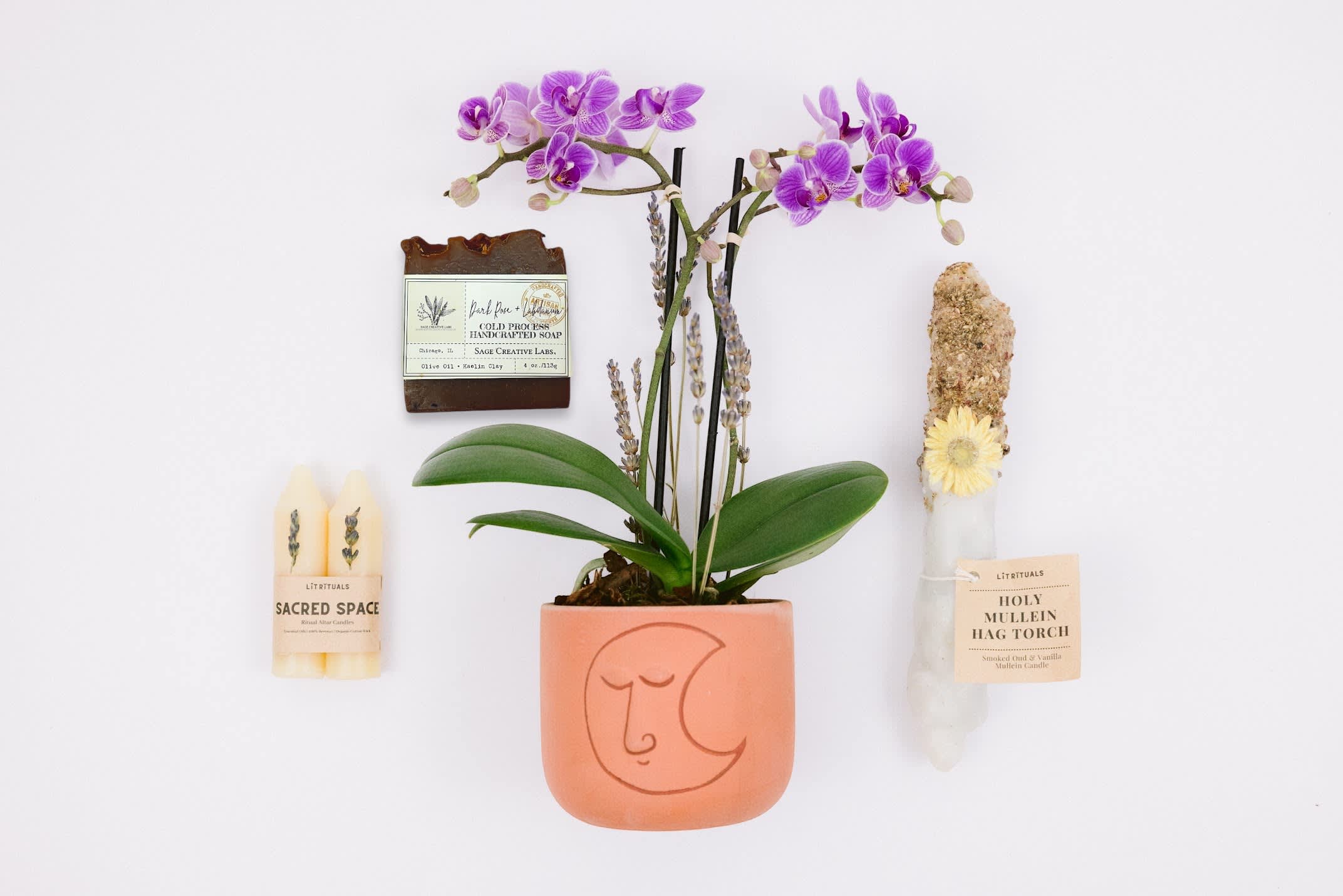 Spiritual Unity Gift Set - SPIRITUAL UNITY GIFT SET  Sol Ambiance is proud to support these artists and makers, and other small businesses, to make our community and the world a better place. Enjoy your gift set!  Mini Phalaenopsis Orchid planted in Accent Decor's clay luna pot.  Lit Rituals Holly Mullein Hag Torch This Hag Torche is essentially a candle (another common name for it is "witch candle") made from mullein stalks and pure white beeswax. Each stalk is lovingly dipped in an herbal medley of mugwort, rose, yarrow and chamomile to heighten our ability to see through the veil and communicate with ancestral spirits. The yarrow offers protection to warn off any negative spirits and vibes.   Lit Rituals Altar Candle “Sacred Space”  These altar candles are made with 100% beeswax. They come in bundles of 2. Sacred Space candles were created to aid in times of ritual.  These lavender essential oil candles will release a calming scent when you burn them, and have a gorgeous piece of dried lavender attached to the top of the candle.  Burn these when you need some relaxation in your meditation. Please remove adornments before burning.  Sage Creative Labs- Dark Rose soap.  Handcrafted in Chicago, Illinois, this soap smells like a dream. These Cold Process soaps are include luxurious oils such as olive oil, virgin coconut oil, palm oil, and other essential oils to give this soap a deep floral scent to enjoy in the bathroom.  