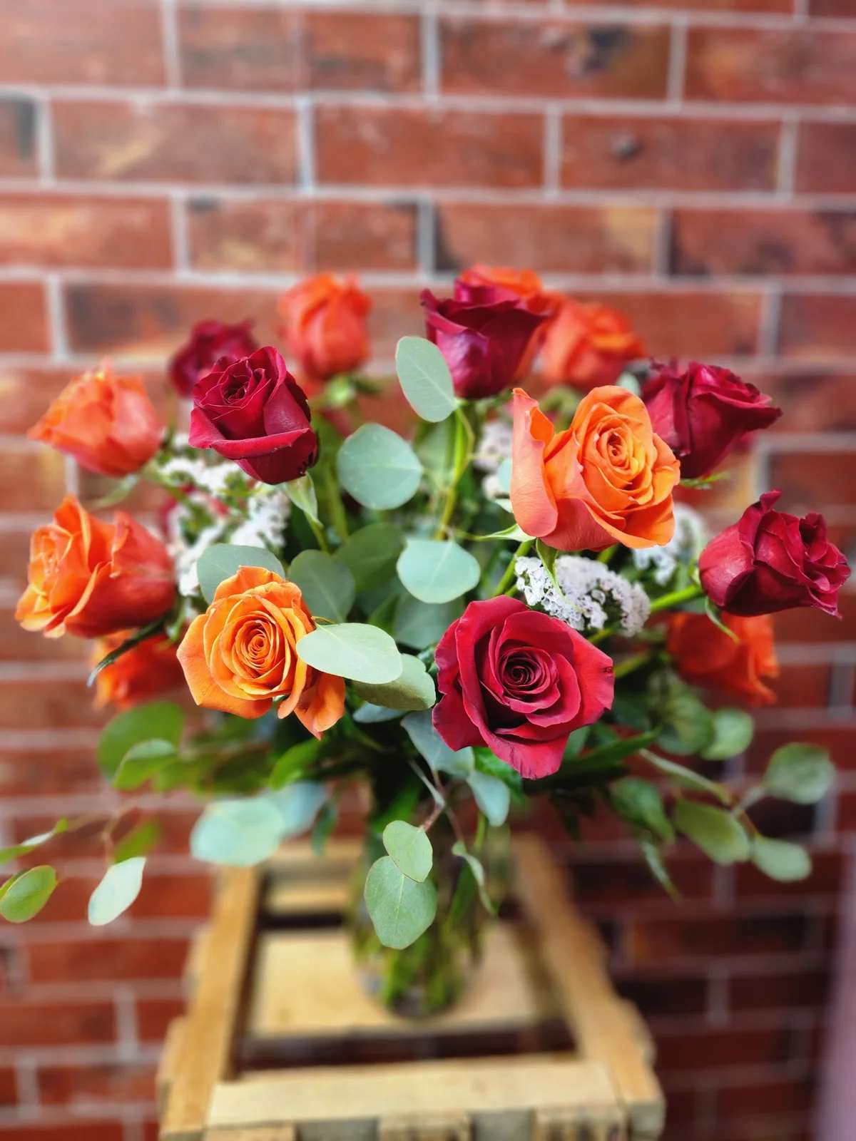 Bouquet of red and orange roses with eucalyptus in a vase