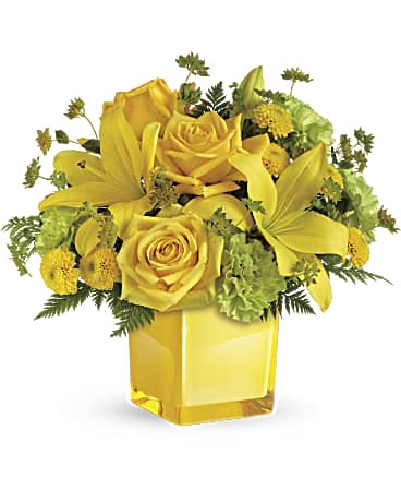 Yellow roses and lilies arranged in a square glass vase