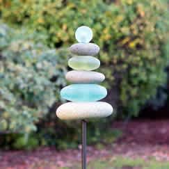 Stacked smooth stones on a metal stake in a garden.