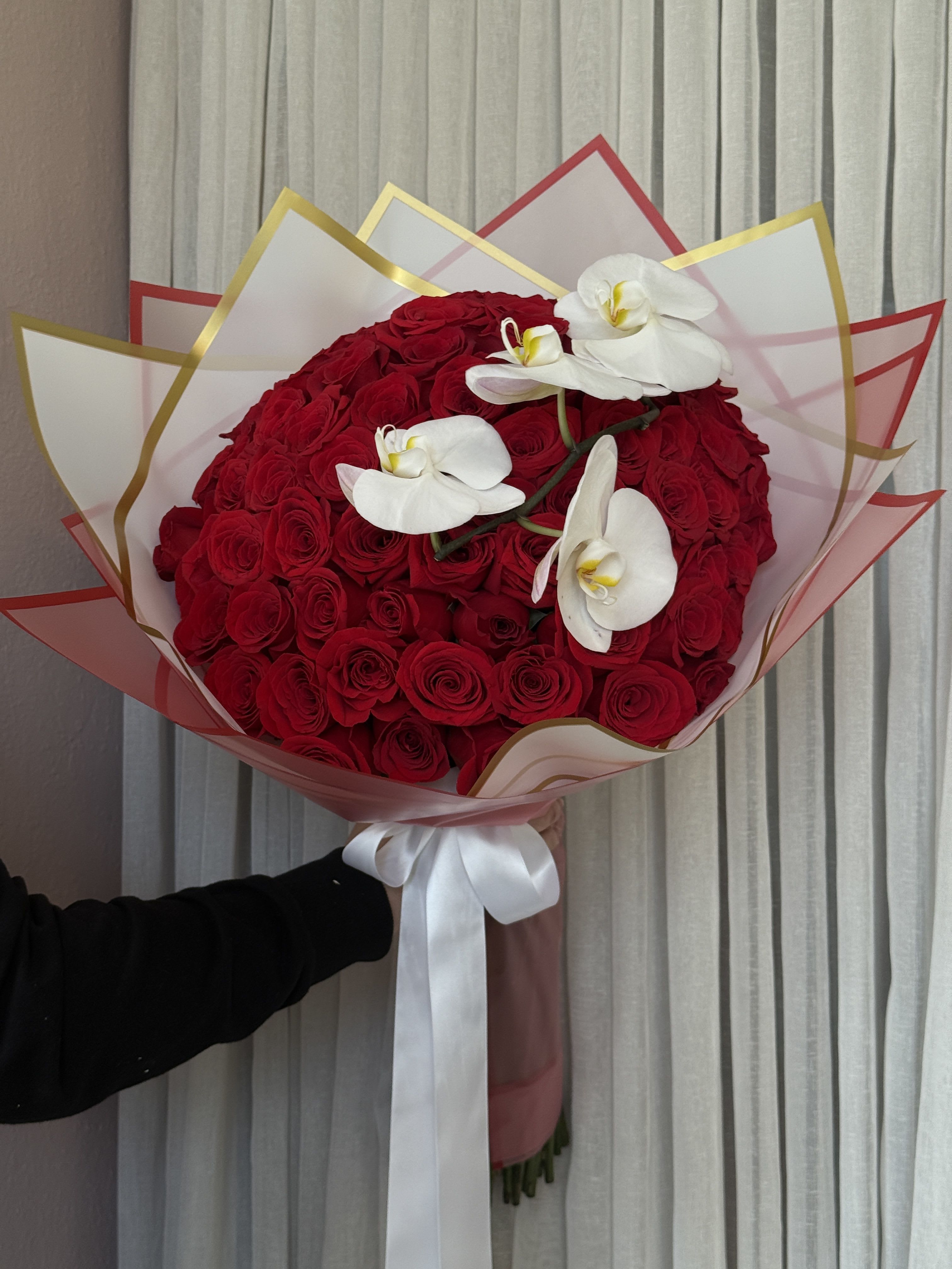 Large bouquet of red roses with white orchids and a white ribbon