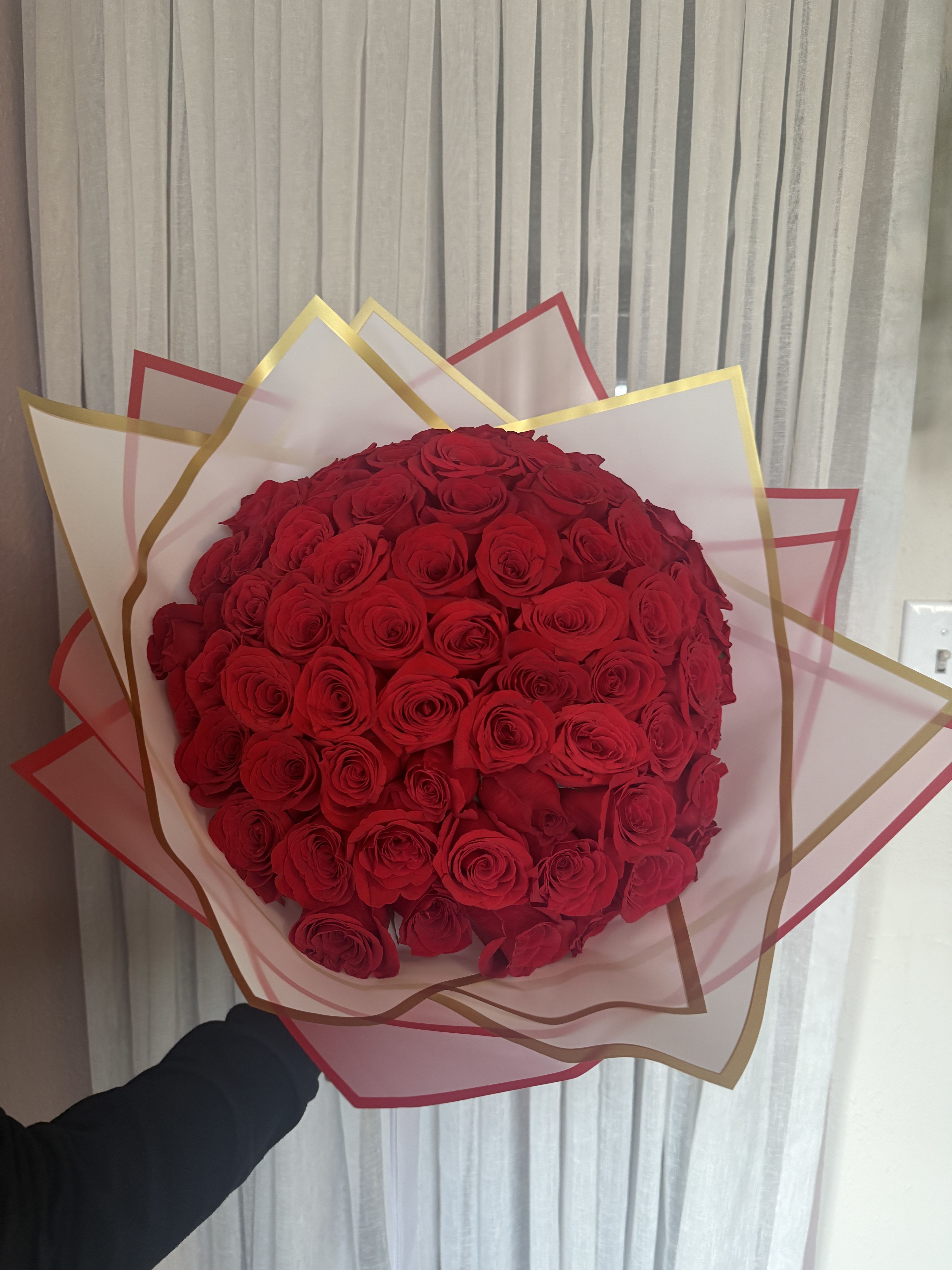 Large bouquet of red roses wrapped in pink and gold paper