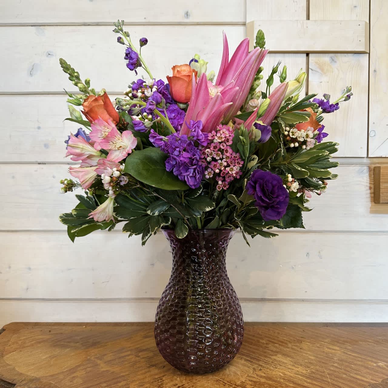 Pink and purple mixed bouquet in a dark glass vase